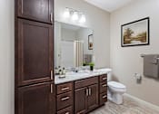 Thumbnail 24 of 44 - a bathroom with wooden cabinets and a toilet and a sink at The Winslow 62+ Apartments, West St Paul, 55118