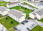 Thumbnail 52 of 57 - A large building complex with a parking lot in front.