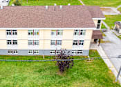 Thumbnail 51 of 57 - A large building with a brown roof and a green lawn in front.