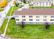 Thumbnail 48 of 57 - A large building with a brown roof is surrounded by a grassy area.