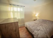 Thumbnail 20 of 57 - A bedroom with a bed, nightstand, and lamp.