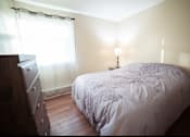 Thumbnail 23 of 57 - A bed with a white comforter and a lamp on a side table.