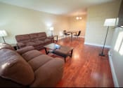 Thumbnail 26 of 57 - A living room with a brown couch and a wooden floor.