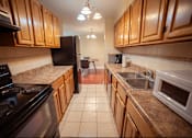 Thumbnail 30 of 57 - A kitchen with wooden cabinets and a black stove top oven.