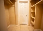 Thumbnail 25 of 57 - A white door is in a hallway with shelves on either side.