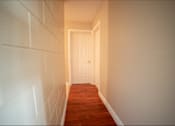 Thumbnail 33 of 57 - A hallway with a white door at the end.