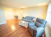 Thumbnail 34 of 57 - A grey couch and a white coffee table in a room with wooden flooring.