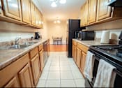 Thumbnail 32 of 57 - A kitchen with wooden cabinets and a black refrigerator.