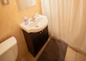 Thumbnail 42 of 57 - A small bathroom with a toilet, sink, and shower curtain.