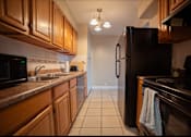 Thumbnail 43 of 57 - A kitchen with a black refrigerator and brown cabinets.