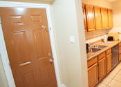 Thumbnail 44 of 57 - A brown door is in a hallway leading to a kitchen.