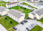 Thumbnail 6 of 28 - A parking lot is in front of a building.