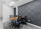 Thumbnail 68 of 83 - a small meeting room with a wooden table and four black chairs at Audenn Apartments, Minnesota, 55438