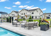Thumbnail 52 of 113 - A poolside area with lounge chairs and a house in the background.