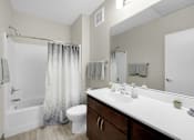 Thumbnail 15 of 55 - A bathroom with a white sink, toilet, and bathtub with grey shower curtain.