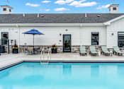 Thumbnail 55 of 113 - A pool in front of a white building with a black fence around it.