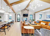 Thumbnail 70 of 113 - A modern living room with a wooden dining table and a stone fireplace.