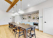 Thumbnail 77 of 113 - A modern kitchen with a long table and chairs.