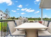 Thumbnail 63 of 113 - A white house with a patio table and chairs.