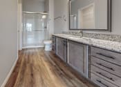 Thumbnail 31 of 32 - A bathroom with a wooden floor and a white door.