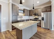 Thumbnail 28 of 32 - A modern kitchen with a granite countertop and stainless steel appliances.