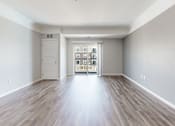 Thumbnail 29 of 32 - A room with wooden floors and a white door leading to a balcony.