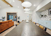 Thumbnail 43 of 52 - A long wooden table is in the middle of a room with a white ceiling and a painting hanging on the wall.