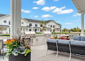 Thumbnail 60 of 113 - A patio with a sofa and chairs overlooking a white building.