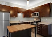 Thumbnail 17 of 55 - A kitchen with brown cabinets and a wooden island.