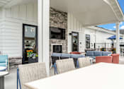 Thumbnail 92 of 113 - A white building with a stone fireplace and a white table and chairs outside.