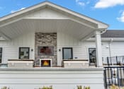 Thumbnail 90 of 113 - A white house with a stone fireplace on the front porch.