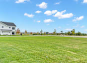 Thumbnail 88 of 113 - A large grassy field with a house in the background.