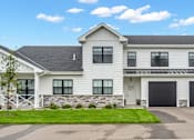 Thumbnail 43 of 113 - A large white house with a black garage door.