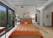 Thumbnail 5 of 55 - A bedroom with a large bed and a balcony with a view of trees.