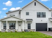 Thumbnail 44 of 113 - A white house with a black garage door.