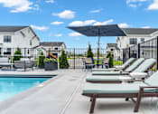Thumbnail 53 of 113 - A poolside area with lounge chairs and umbrellas.