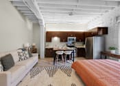 Thumbnail 4 of 55 - A modern living room with a white couch and a kitchen area in the background.
