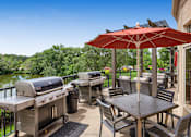 Thumbnail 32 of 49 - a patio with barbecue grills and tables with umbrellas