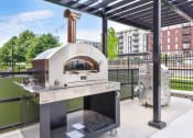 Thumbnail 42 of 53 - a pizza oven on a patio with a grill in the background