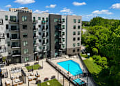 Thumbnail 2 of 88 - A large apartment complex with a pool and a green lawn.