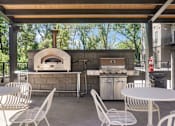 Thumbnail 11 of 88 - A patio with a table, chairs, and a pizza oven.