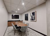 Thumbnail 14 of 71 - A conference room with a table, chairs, and two framed pictures on the wall.