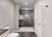 Thumbnail 44 of 65 - a bathroom with a shower and a toilet and a sink at Ardor on the Bluffs South Loop Residences Apartments, Bloomington