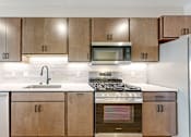 Thumbnail 54 of 65 - a kitchen with wooden cabinets and stainless steel appliances at Ardor on the Bluffs South Loop Residences Apartments, Bloomington, Minnesota