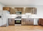 Thumbnail 59 of 65 - a kitchen with stainless steel appliances and wooden cabinets at Ardor on the Bluffs South Loop Residences Apartments, Bloomington
