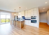 Thumbnail 27 of 76 - A kitchen with a wooden floor and white walls.