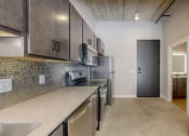 Thumbnail 26 of 65 - a renovated kitchen with stainless steel appliances and a door to a hallway at Ardor on the Bluffs South Loop Residences Apartments, Bloomington, 55425