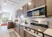 Thumbnail 11 of 65 - a modern kitchen with stainless steel appliances and cabinets at Ardor on the Bluffs South Loop Residences Apartments, Bloomington