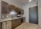 Thumbnail 30 of 65 - an empty kitchen with stainless steel appliances and wooden cabinets at Ardor on the Bluffs South Loop Residences Apartments, Bloomington, Minnesota