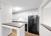Thumbnail 24 of 83 - A kitchen with white cabinets and a black fridge.